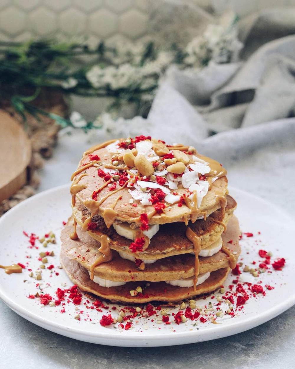 Two Islands Pea Protein pancakes stacked with banana slices and topped with freeze dried raspberries